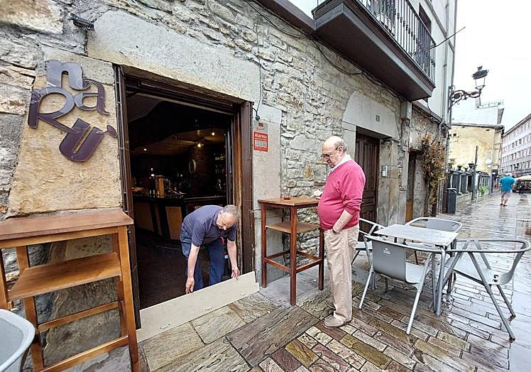 Imagen principal - Colocando una tabla en el bar Narú para evitar otra inundación. Cubos y fregonas en la notaría Gestión 10 y la peluquería Rabatt, donde entró un palmo de agua. 