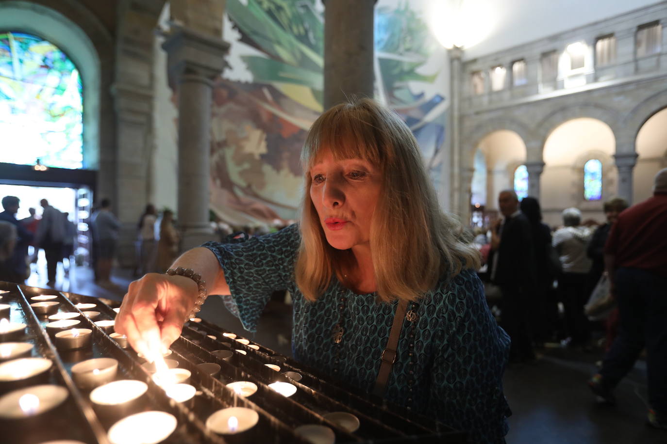 Una mujer enciende una vela dentro del santuario.