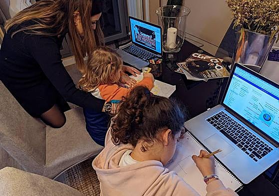 Una madre ayuda a sus hijas a hacer los deberes en casa.