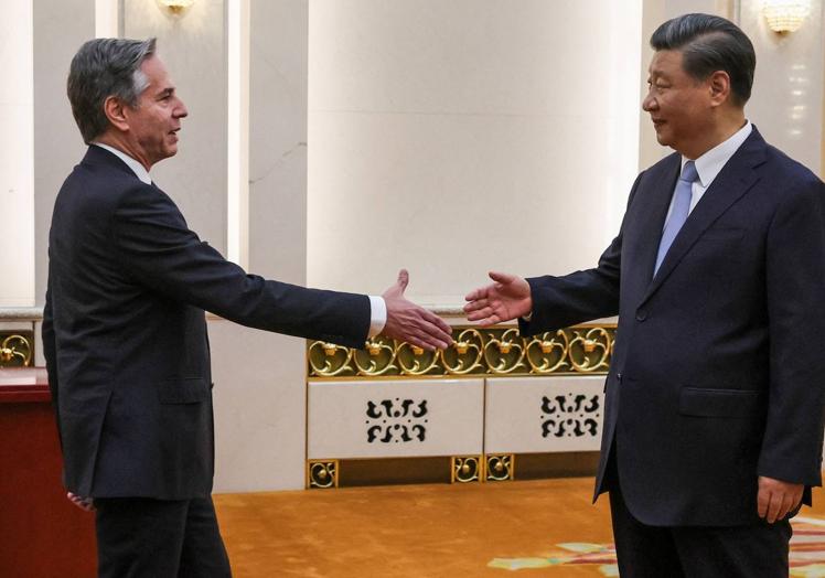 Antony Blinjken y Xi Jinping estrechan sus manos.