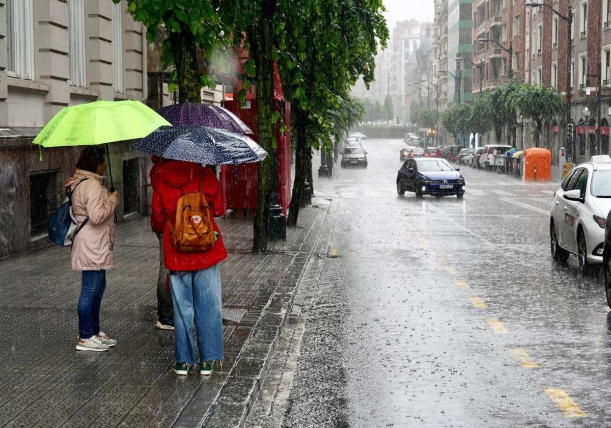 Varias personas aguardan un taxi en la parada de Moyua, en plena tormenta este pasado domingo.