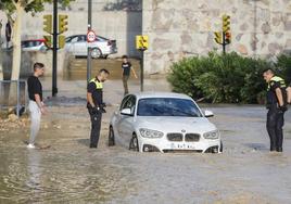 Agentes de la Policía Local observan un coche arrastrado por la tormenta caída este jueves en Zaragoza.