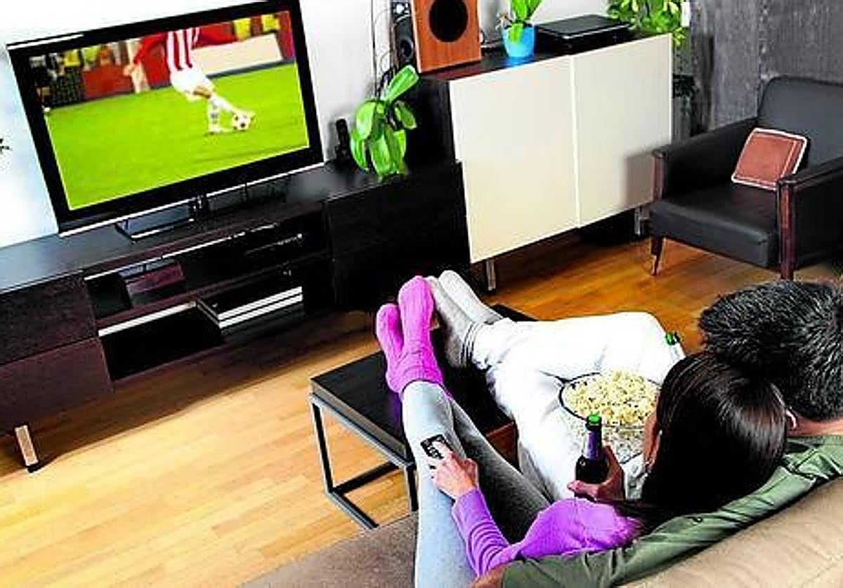 Una pareja ve un partido de fútbol en la tele.