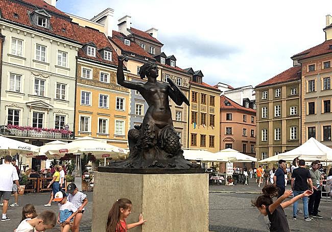 Varios niños juegan junto a la estatua de La sirenita en la Plaza del Mercado.