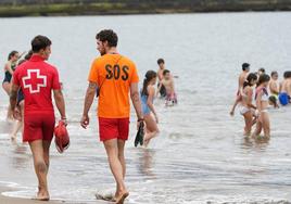 Dos socorristas y jóvenes bañistas, esta mañana en la playa de Ereaga.