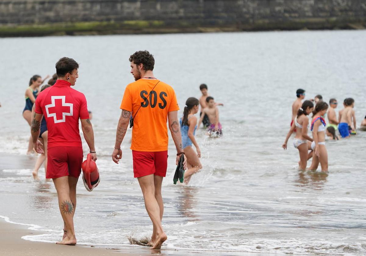 Dos socorristas y jóvenes bañistas, esta mañana en la playa de Ereaga.