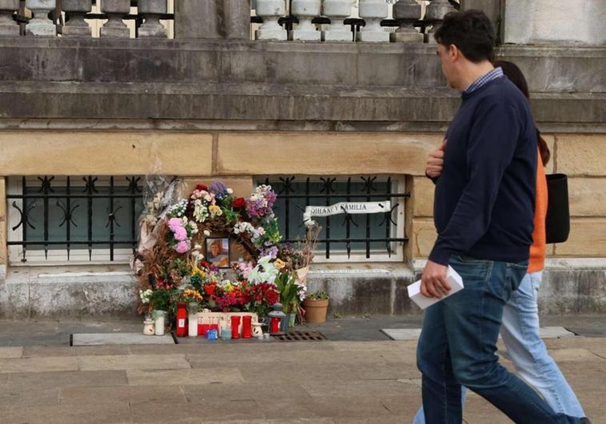 Dos personas observan unas flores y velas en el lugar en el que Lukas Agirre fue apuñalado.