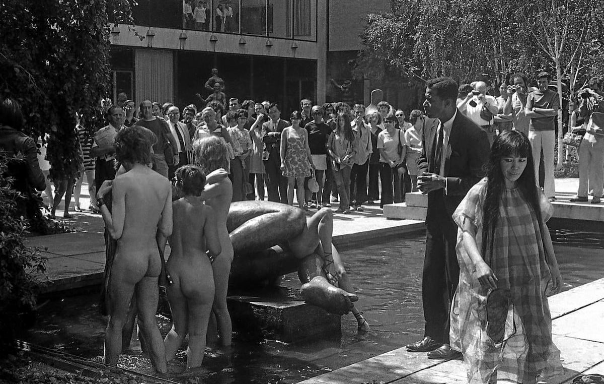 Un oficial de seguridad pide a varias personas desnudas que salgan del estanque del MoMA durante una performance de Kusama, a la derecha.