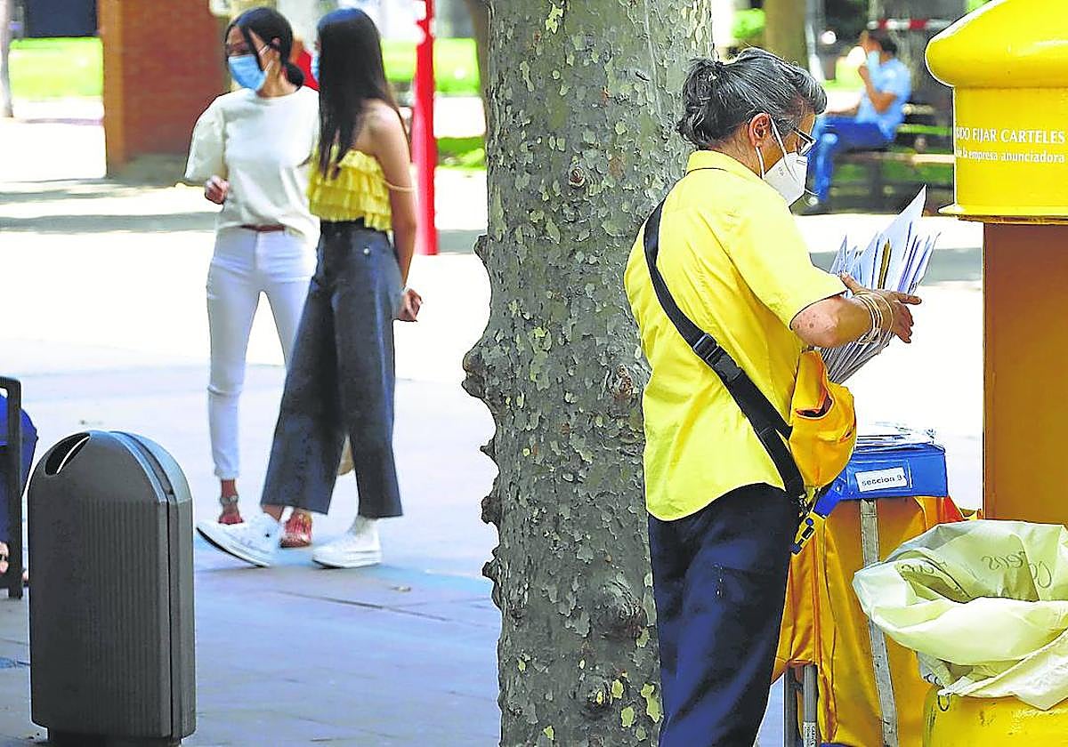 Una cartera recoge las cartas de un buzón ubicado en calle La Estación.