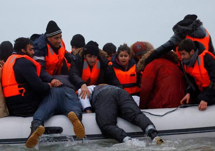 Imagen principal - Arriba, una imagen de archivo de emigrantes en el paso de Calais. Abajo, una patrullera francesa en Calais y emigrantes capturados en un barco galo.