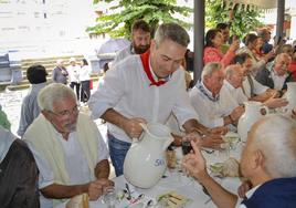 Un participante en la comida de la Cofradía de San Roque de Llodio sirve vino a sus compañeros.