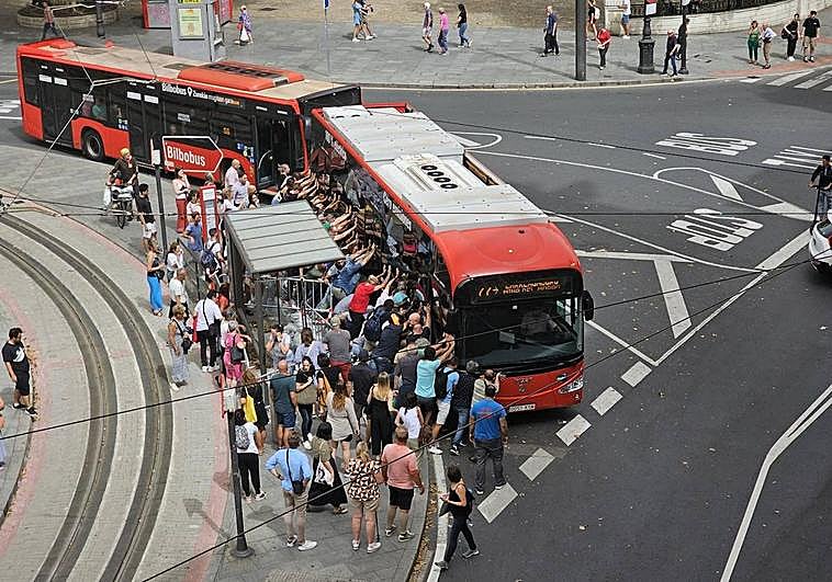Decenas de personas empujan el autobús ante una gran expectación.