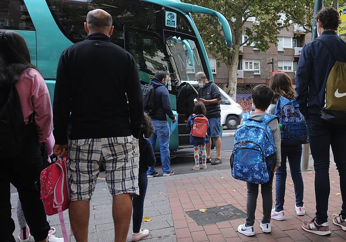 Familias esperan a que sus hijos monten en el autobús escolar.