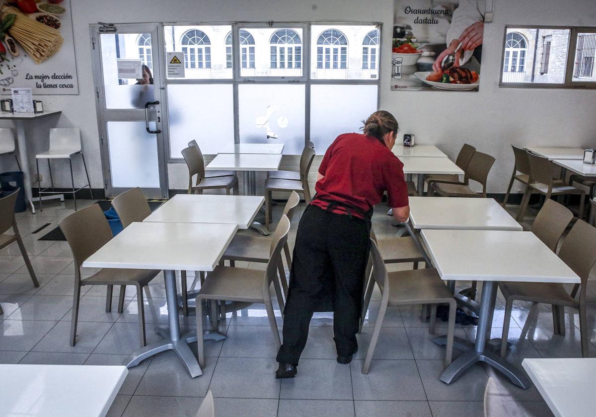 Una trabajadora de la cafetería de Santiago coloca unas mesas.