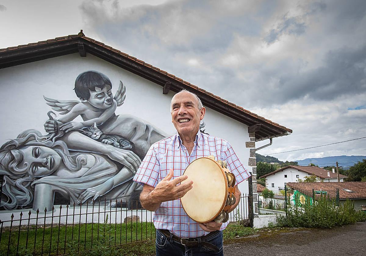 Julián Mari toca la pandereta ante el grafiti de su caserío.