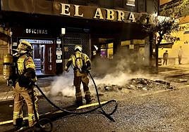 Dos bomberos sofocan el incendio que calcinó dos contenedores.