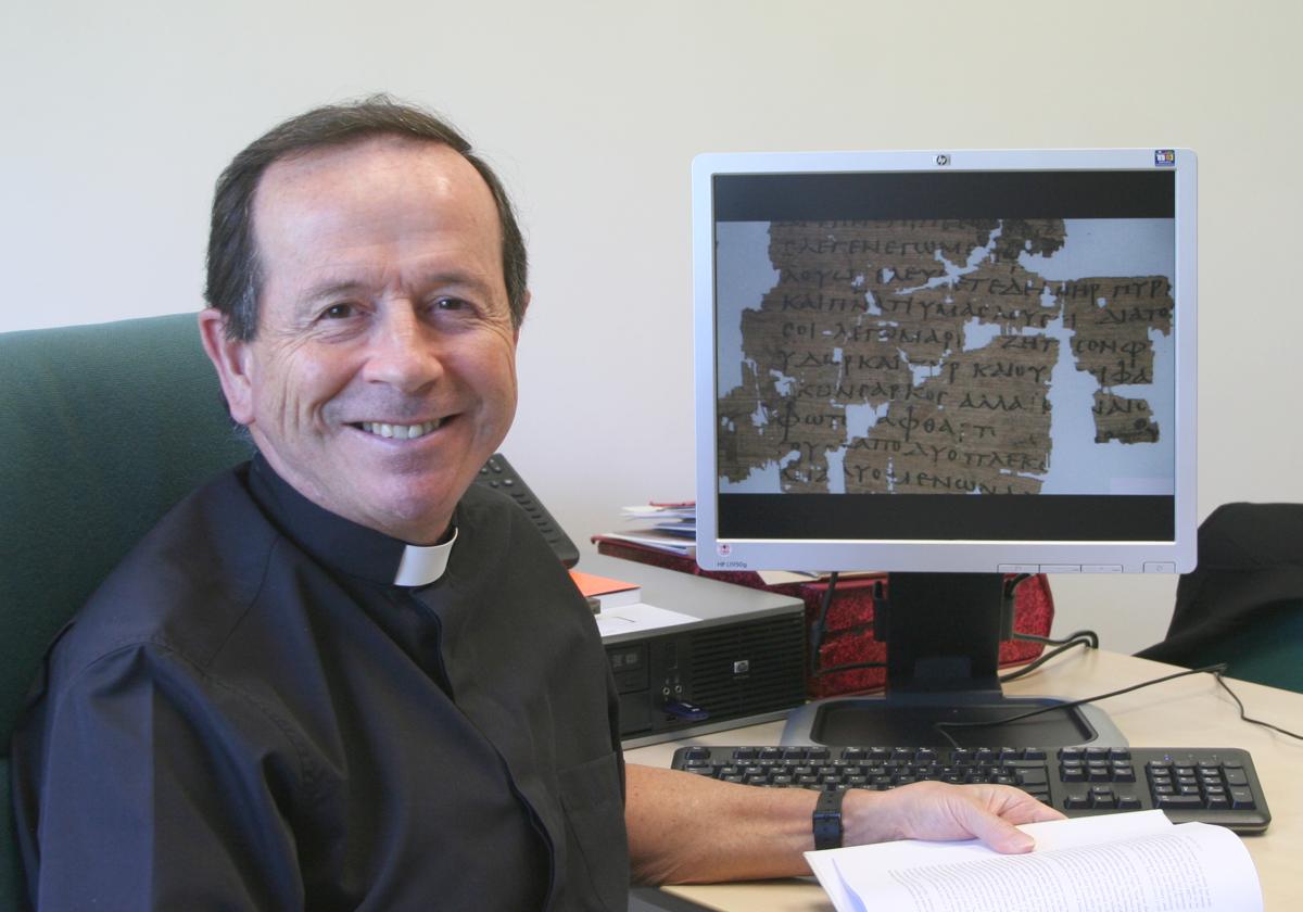 El sacerdote y papirólogo Juan Chapa Prado junto a una imagen de antiguos papiros digitalizados.