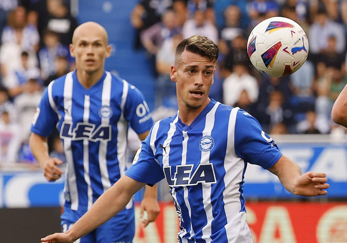 Blanco, en primer plano, intenta controlar el balón mientras Guridi observa la jugada de fondo.