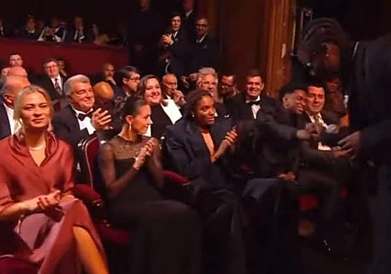 Rema choca los cinco con Alejandro Balde en presencia de la Balón de Oro Aitana Bonmatí, en el medio.