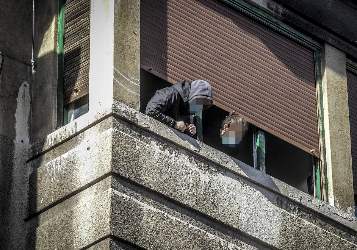 Dos okupas observan la comitiva judicial en una vivienda okupa en Los Herrán.