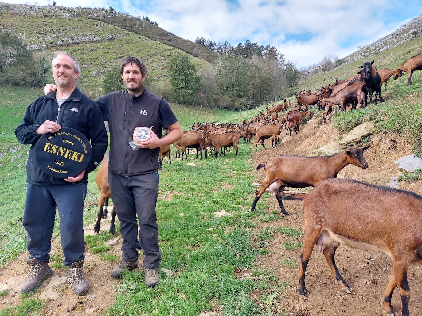 Gorka e Iban Muniozguren muestran la txapela y una pieza del queso ganador.