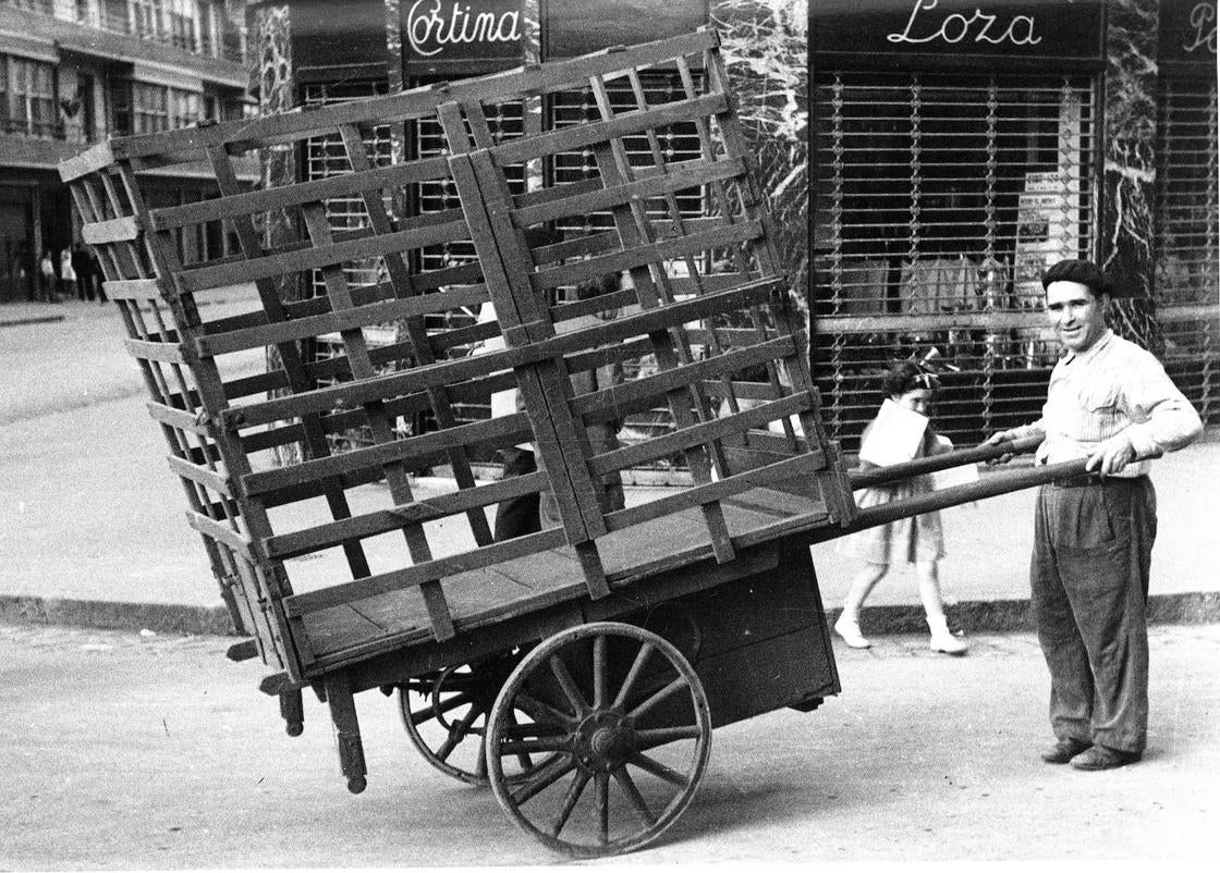 En la foto va de vacío, pero la leña y el carbón fueron combustibles esenciales para mantener calientes las casas y dar vida a las tradicionales 'cocinas económicas'. El de la imagen es Manuel Gil, más conocido como 'Chatillo Manzanilla', un sevillano que desempeñó mil oficios en Bilbao: además de repartidor de leña, fue torero cómico, pero también fotógrafo callejero, pastelero, zapatero, empapelador, cristalero, electricista, fontanero y vendedor de pintxos de bacalao.