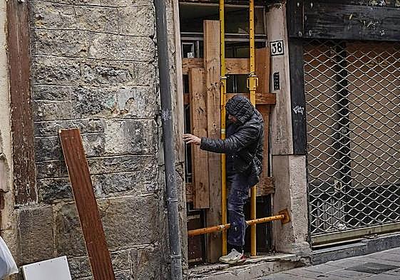 Un operario sale a duras penas del portal tapiado.