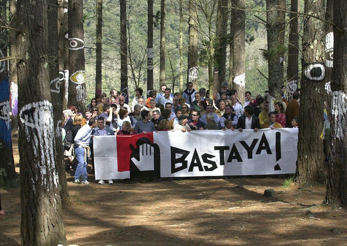 Imagen secundaria 1 - Arriba, pintadas contra al artista. Abajo, una manifestación en el Bosque de Oma en apoyo al pintor e Ibarrola, junto el lazo azul que creó.