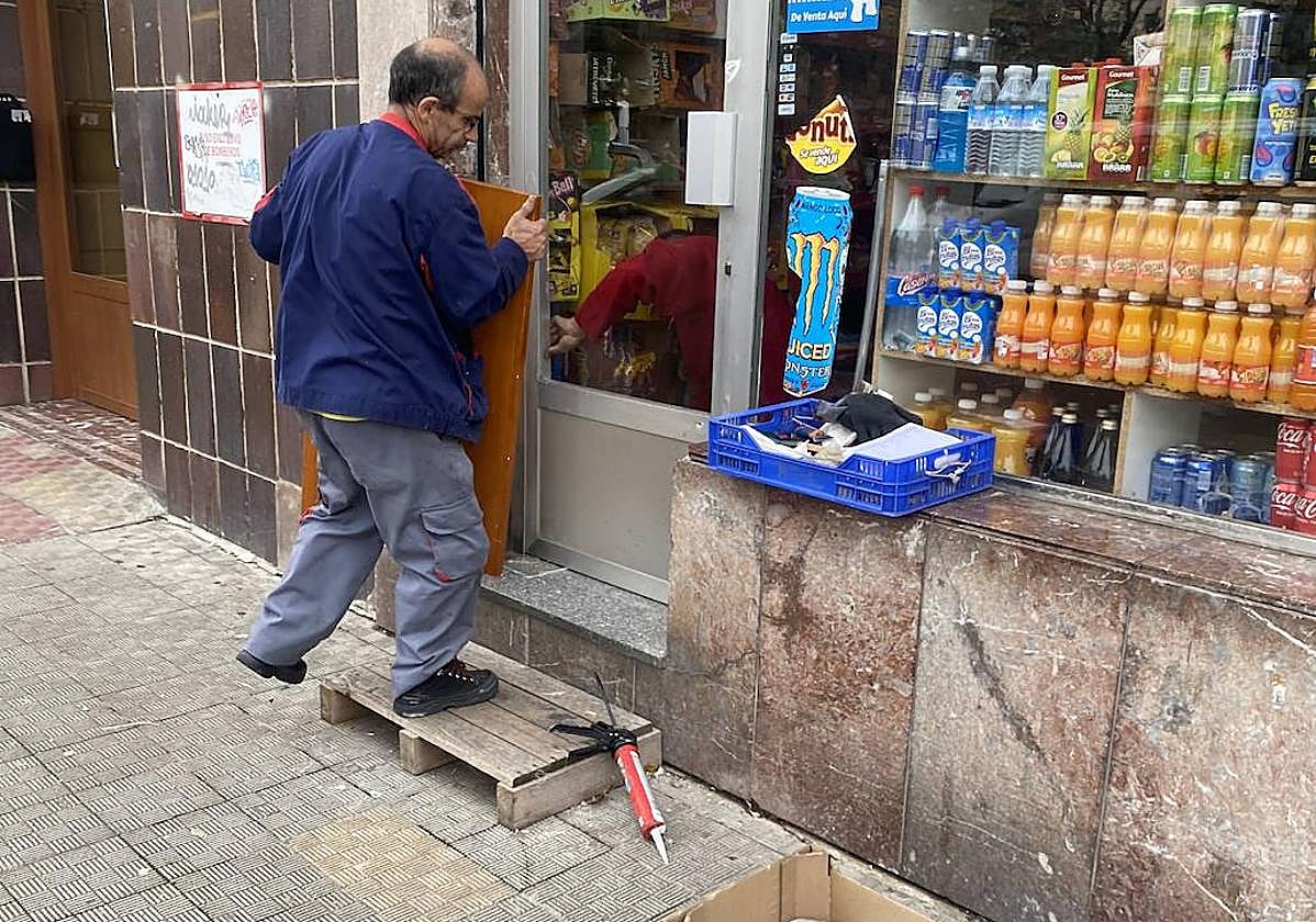 Un operario ultima el arreglo de la puerta fracturada por los asaltantes.