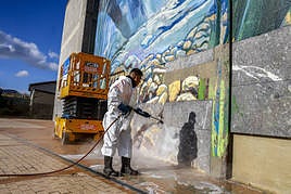 Un operario elimina las pinturas de la fachada del edificio.