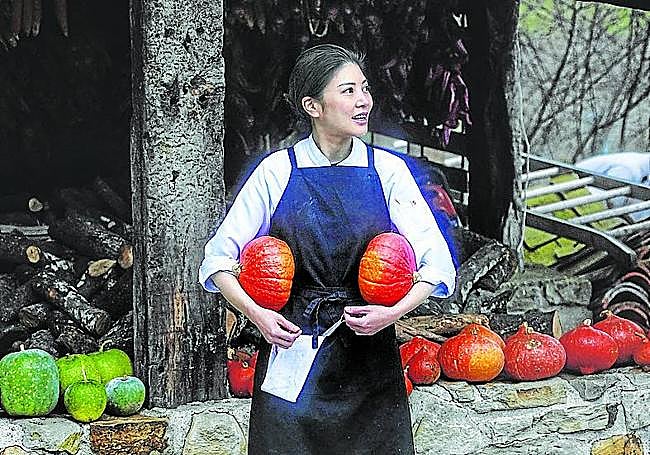 Una empleada junto al huerto y la leña que emplean.
