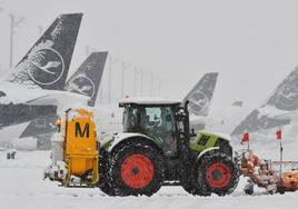 Un tractor quitanieves se aplica a fondo en la pista del aeropuerto de Munich.