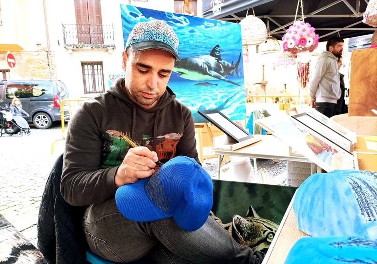 El artista durangués Aratz Azpiri diseñando una de viseras en la feria de artesanos de Abadiño.