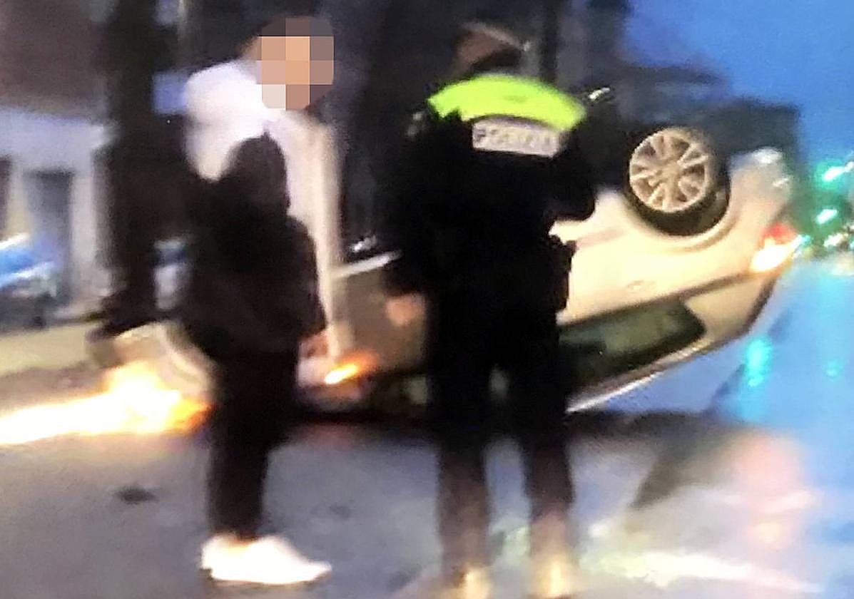 Un agente municipal con el conductor accidentado, ayer en la Avenida de los Huetos.