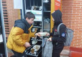 Dos alumnos depositan menús del comedor escolar en la máquina habilitado en Los Llanos.