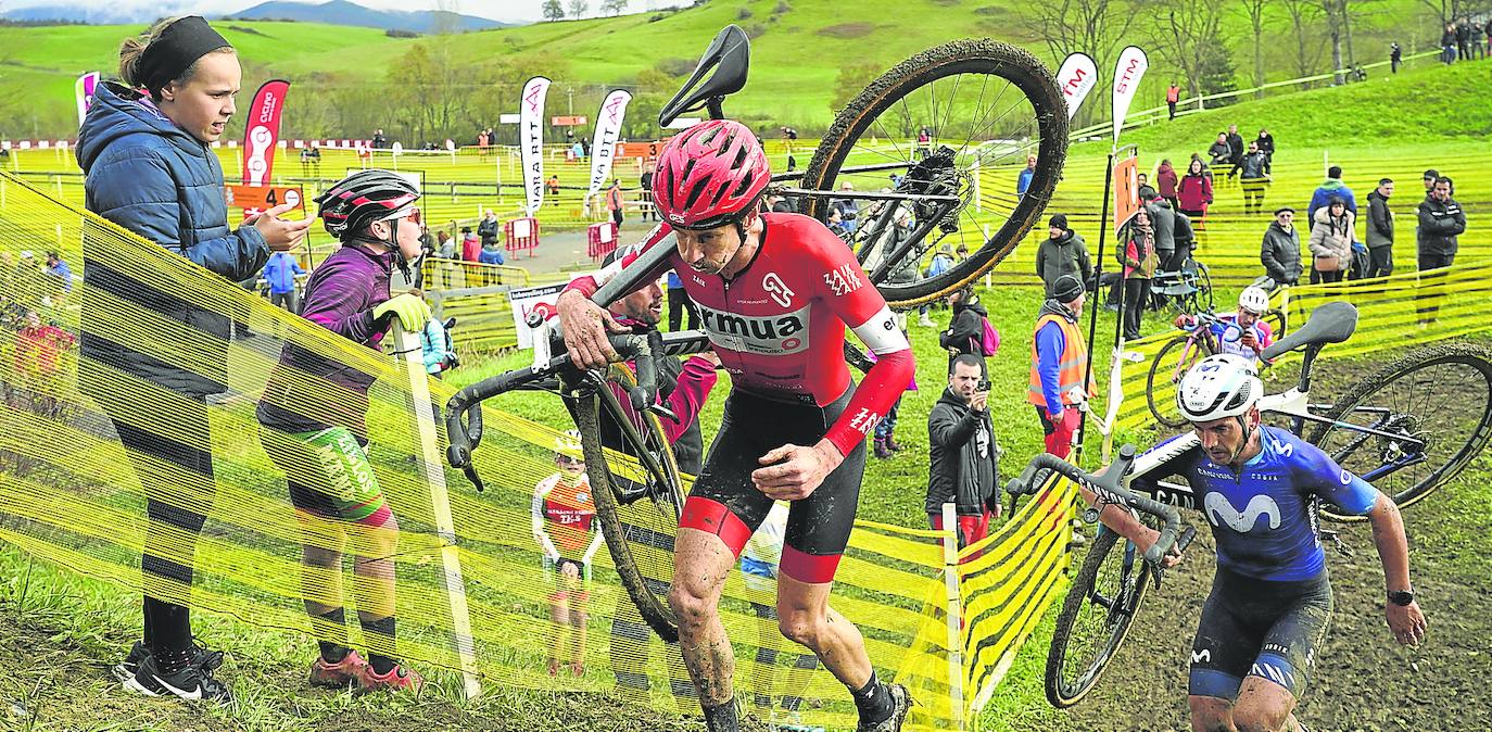 Aitor Hernández asciende un tramo de barro con su bicicleta al hombro por delante del rutero Gorka Izagirre, con el que tuvo un bonito duelo.