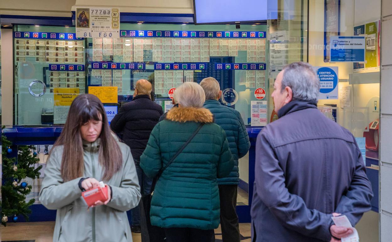 Varios clientes de un despacho de lotería de Vitoria hacen cola para ser atendidos. 