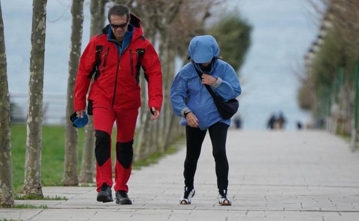 Dos ciudadanos pasean por Punta Galea con dificultad por las intensas ráfagas de viento. 