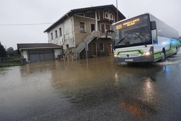 Un autobús circula por una zona inundada por las fuertes lluvias en Asua. 