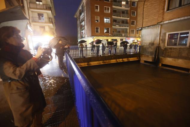 Un grupo de vecinos acuden a uno de los puentes en los que se ve la subida del río Butrón en Mungia. 