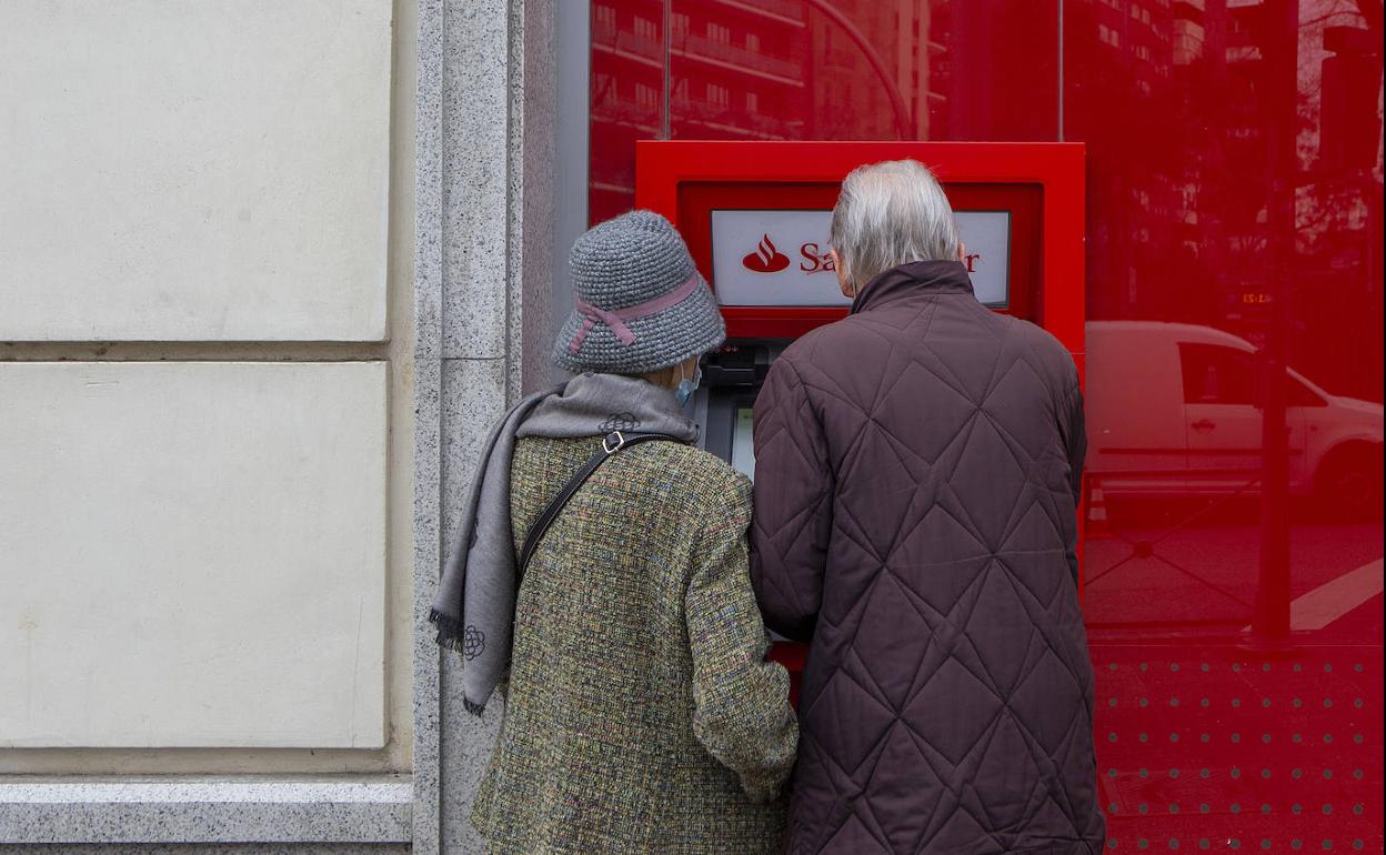 Una pareja de jubilados utilizan un cajero automático de un banco en Madrid. 