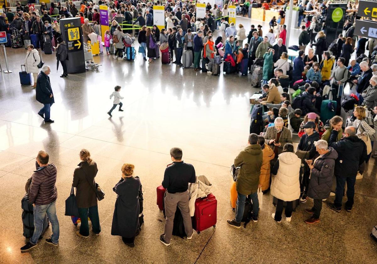 Imagen principal - Arriba, largas colas en el 'hall' de salidas de Loiu. A la izquierda, empleados de una empresa de transporte cargan en furgonetas las maletas que se han quedado en tierra. A la derecha, usuarios reciben información de parte de una trabajadora con las cintas transportadoras colapsadas.