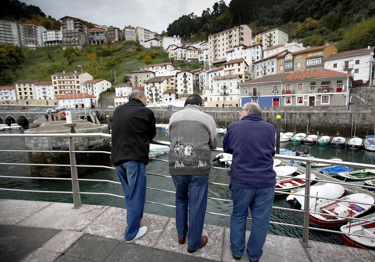 Tras vecinos de Elantxobe disfrutan de las vistas del puerto, donde se encuentra el consultorio médico.