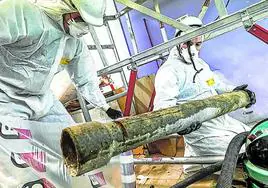 Dos trabajadores retiran un tubo con amianto en Vitoria.
