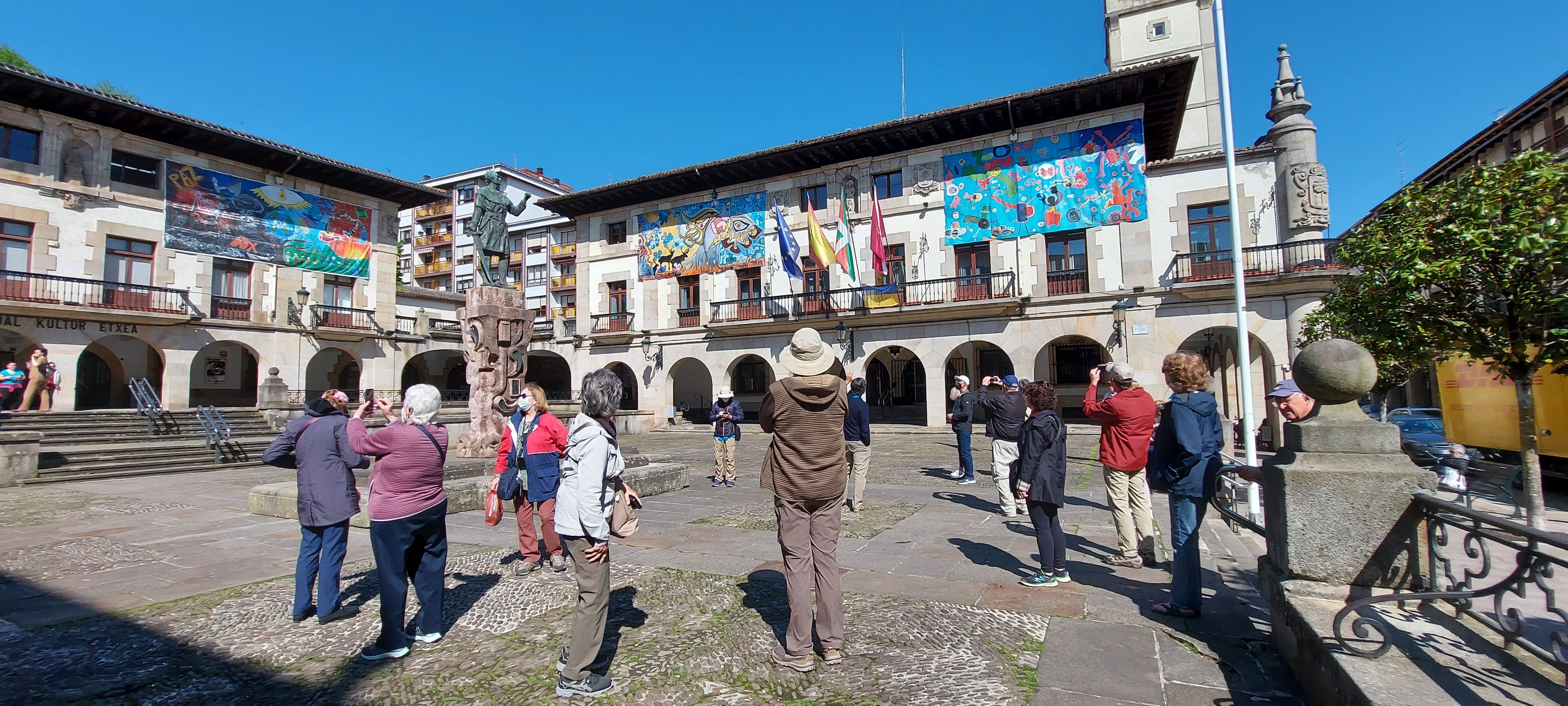 Un grupo de turistas extranjeros fotografía la plaza del Ayuntamiento en Gernika.