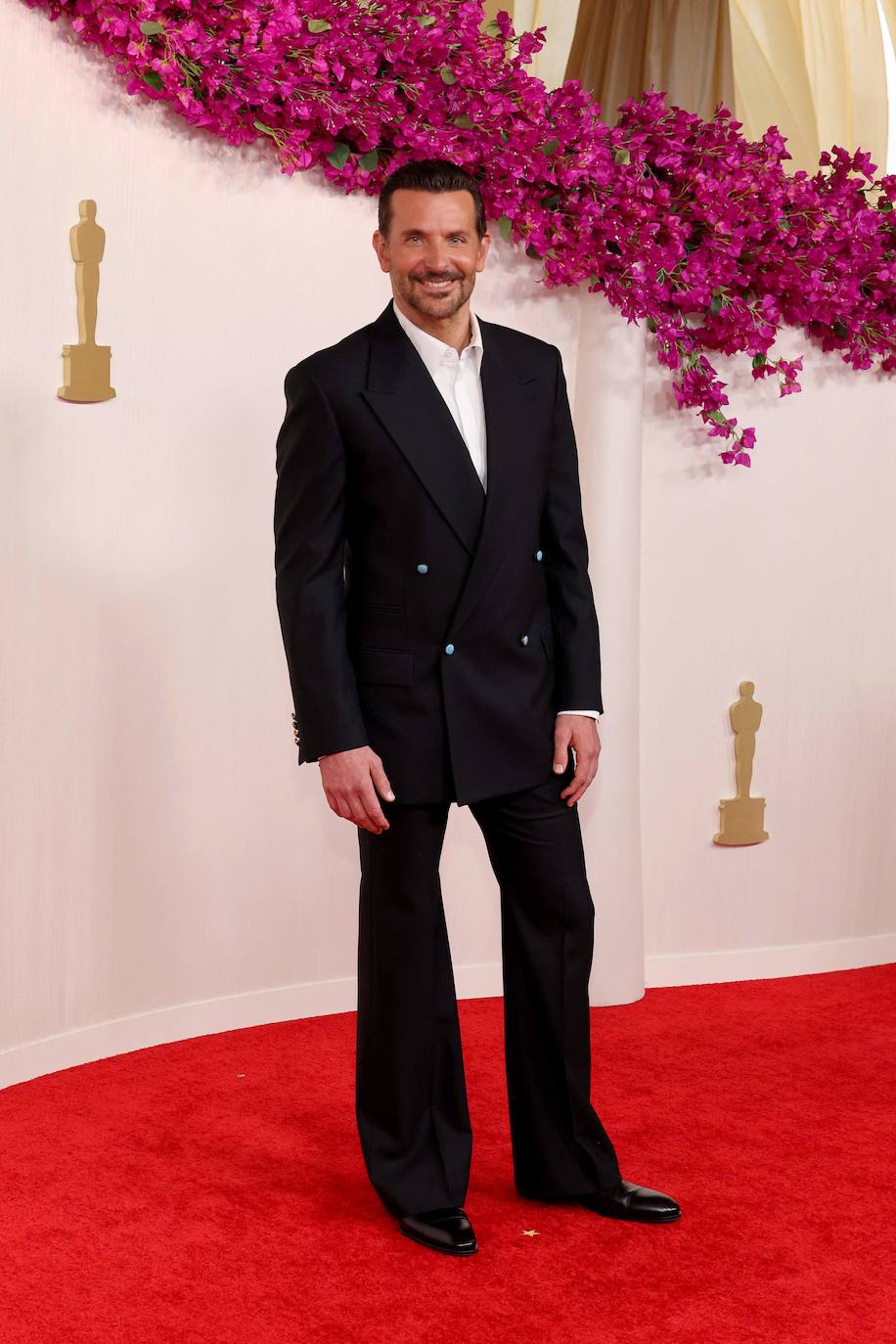 Bradley Cooper ha elegido un traje de chaqueta de Louis Vuitton de pantalón acampanado, camisa blanca y zapatos de vestir. 