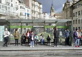 Un grupo de ciudadanos espera la llegada del tranvía en el centro de Vitoria.