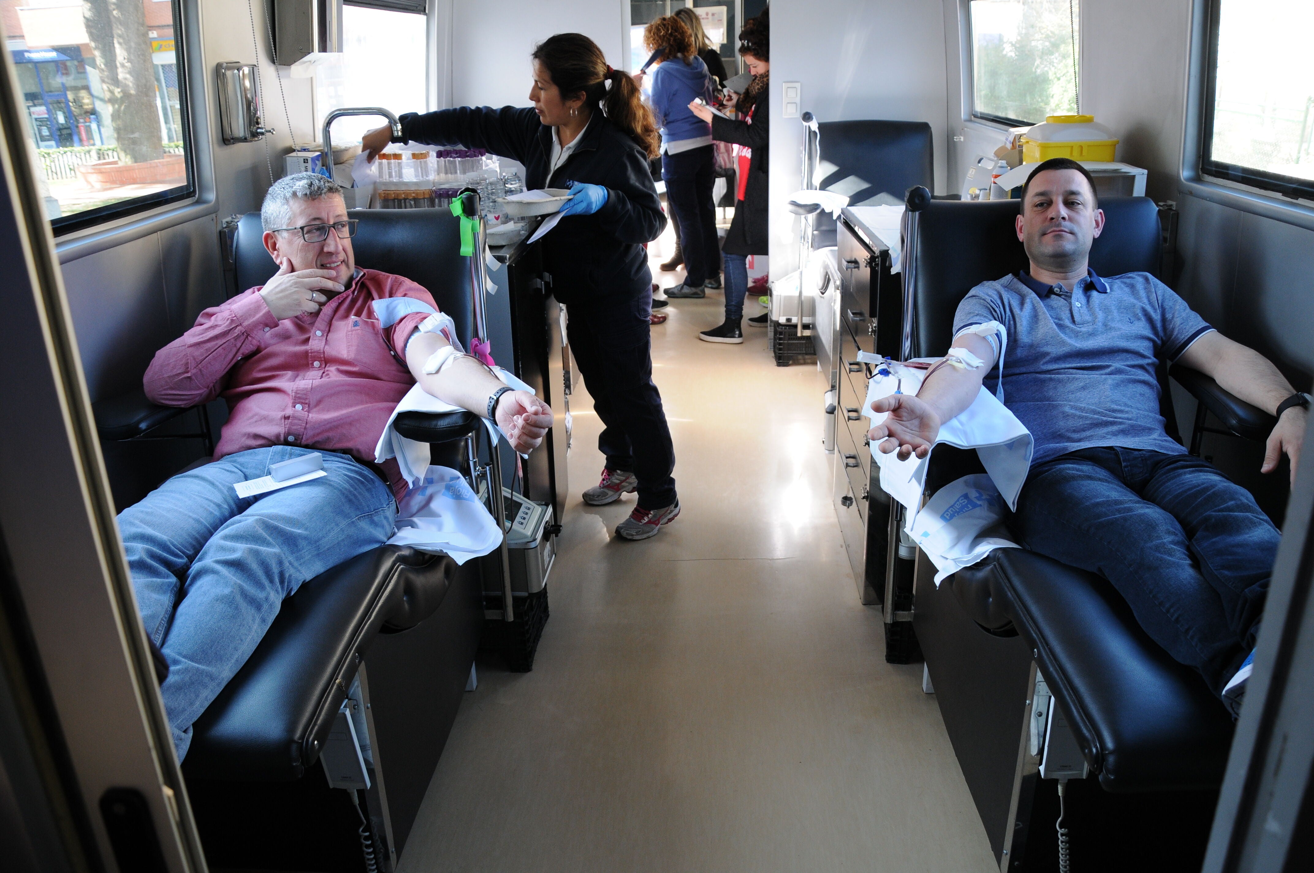 Voluntarios se prestan a donar plasma en un autobús del Banco de Sangre.