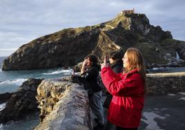Varias turistas sacan fotos del entorno de San Juan de Gaztelugatxe, en Bermeo.