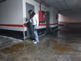 Saioa Pedrueza señala hasta dónde llegó el agua en el garaje comunitario.